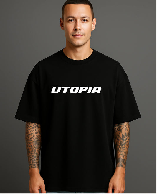 Man in black ATRAYE streetwear T-shirt with 'UTOPIA' print, tattooed arms, grey background