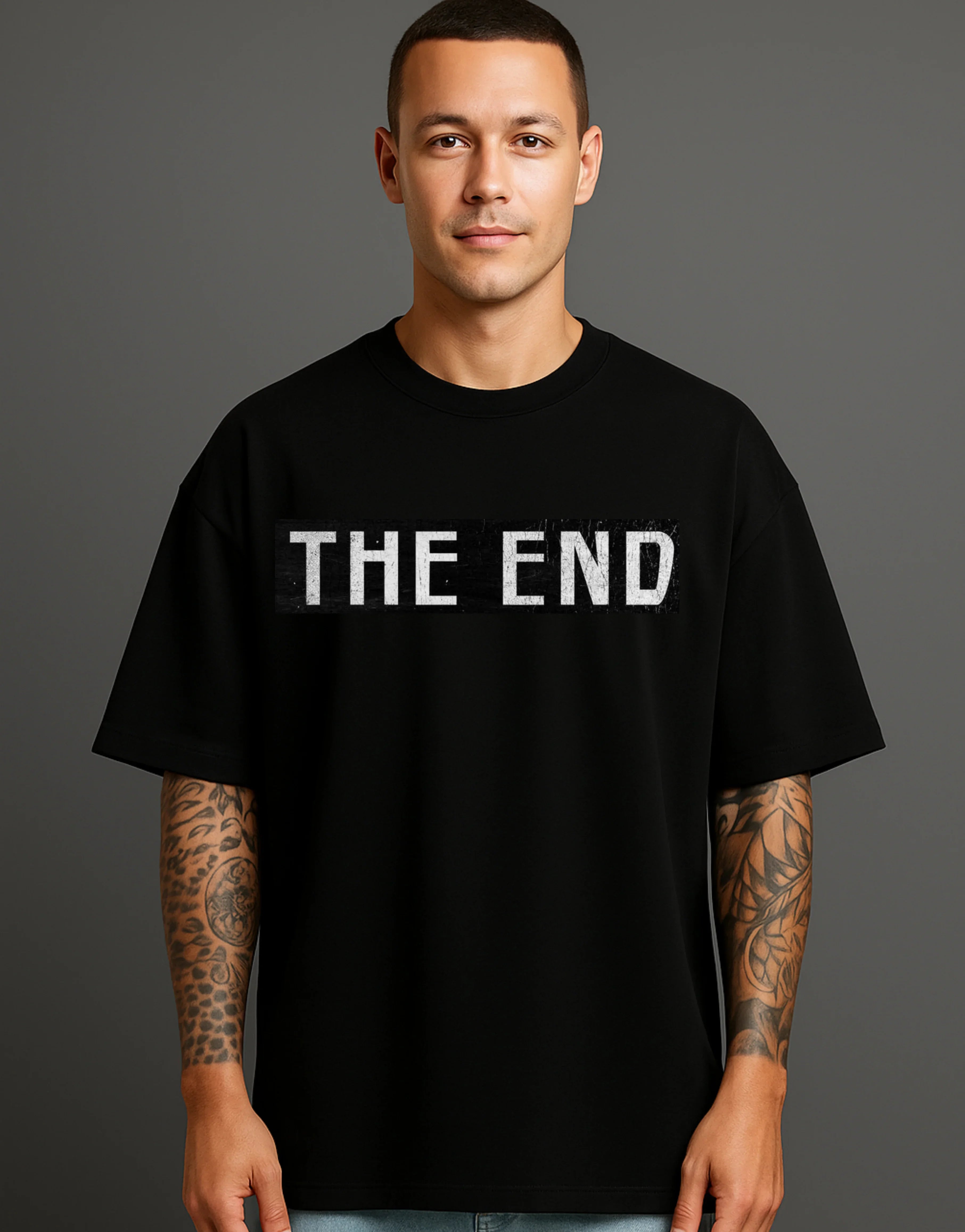 Man wearing black ATRAYE streetwear T-shirt with bold 'THE END' print, tattooed arms, studio background