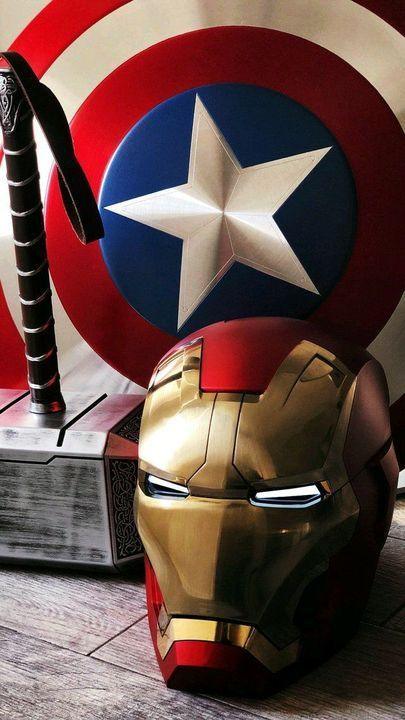 Iron Man helmet, Captain America shield, and Thor hammer on a wooden floor, hero collectibles