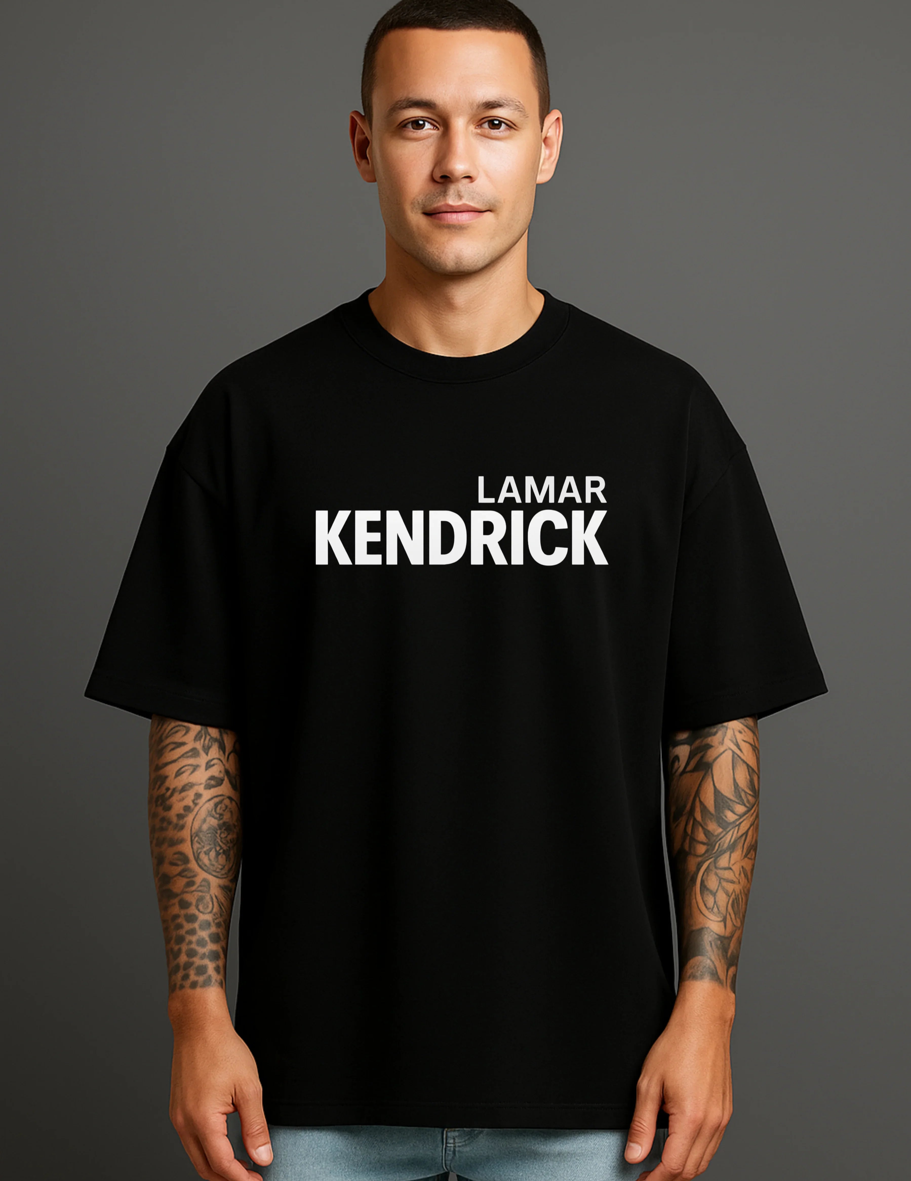 Young man in ATRAYE black streetwear T-shirt with 'Lamar Kendrick' print, tattooed arms.